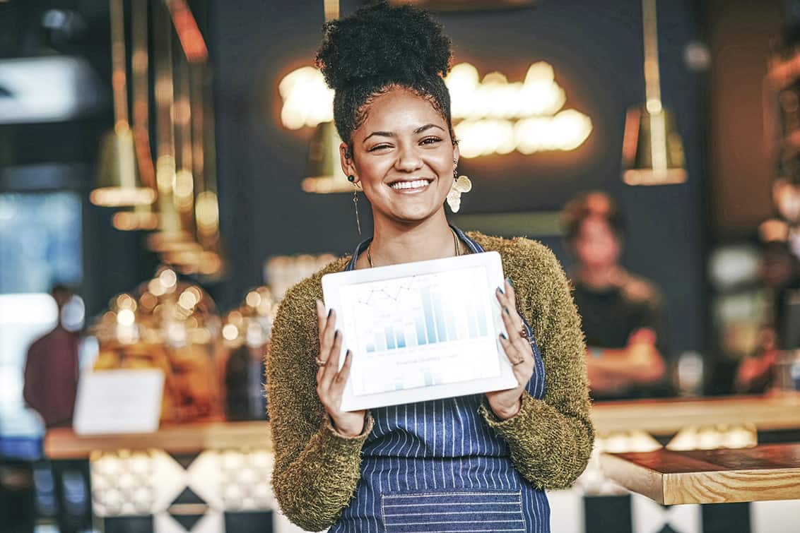 Shot of a young woman holding a digital tablet with a graph on the screen at a coffee shop