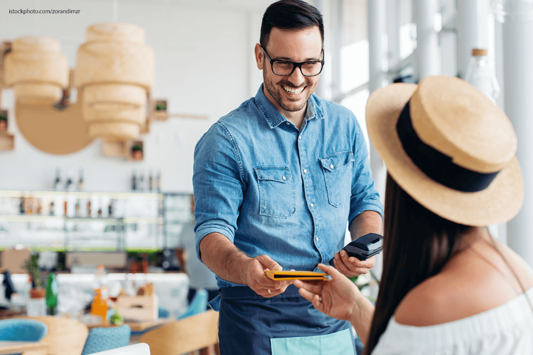 Frau zahlt bei Kellner mit Kreditkarte